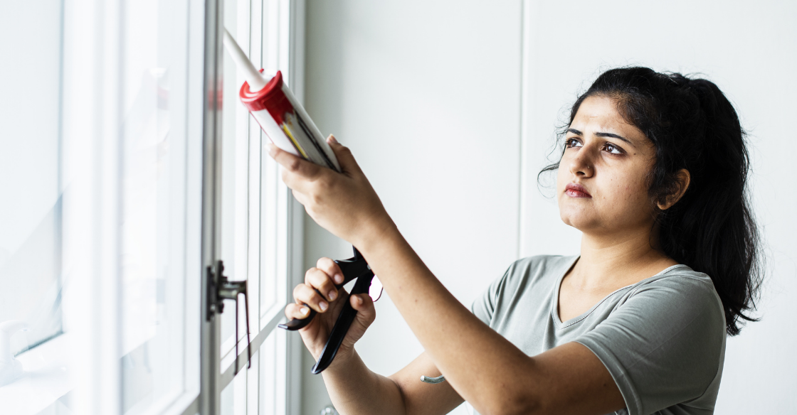 Woman caulking a gap in the patio doors